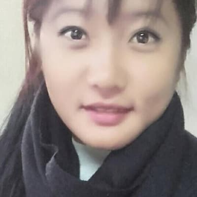 A close portrait of Muna Gurung in a dark scarf, against a plain wall.
